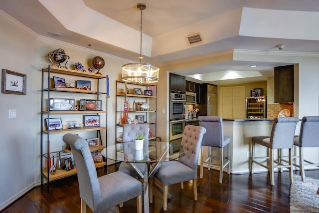 dining space with an inviting chandelier, ornamental molding, dark hardwood / wood-style floors, and a raised ceiling