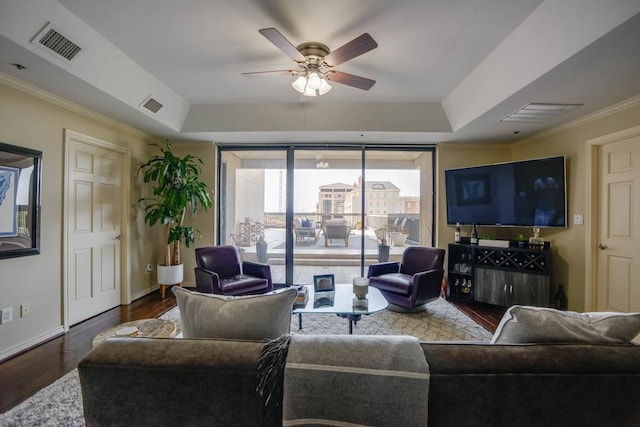 living room featuring a raised ceiling, ceiling fan, ornamental molding, and dark hardwood / wood-style flooring