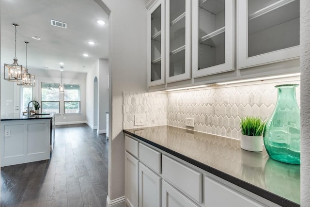 kitchen with sink, dark wood-type flooring, hanging light fixtures, tasteful backsplash, and white cabinets