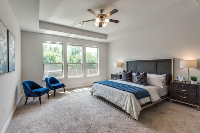 carpeted bedroom with ceiling fan and a raised ceiling