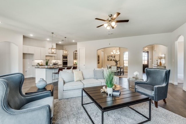 living room with ceiling fan with notable chandelier, sink, and light wood-type flooring