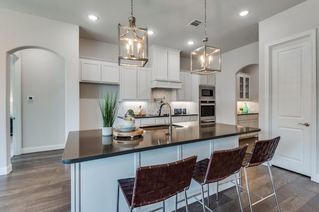 kitchen with stainless steel appliances, white cabinetry, a kitchen island with sink, and a kitchen breakfast bar