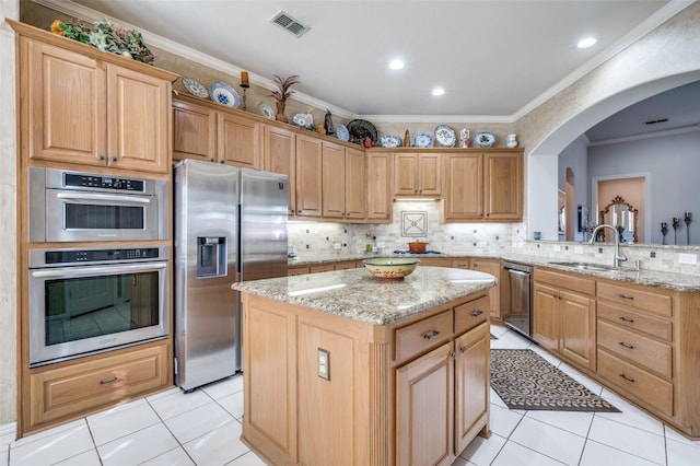 kitchen featuring sink, crown molding, appliances with stainless steel finishes, light stone countertops, and a kitchen island