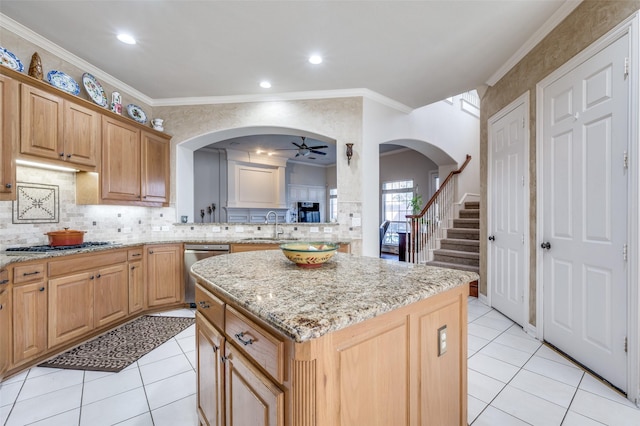 kitchen with light tile patterned flooring, crown molding, light stone counters, appliances with stainless steel finishes, and a kitchen island