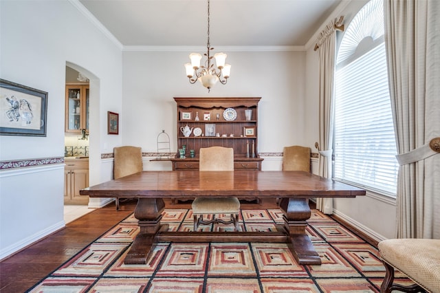 dining space with crown molding, wood-type flooring, and an inviting chandelier