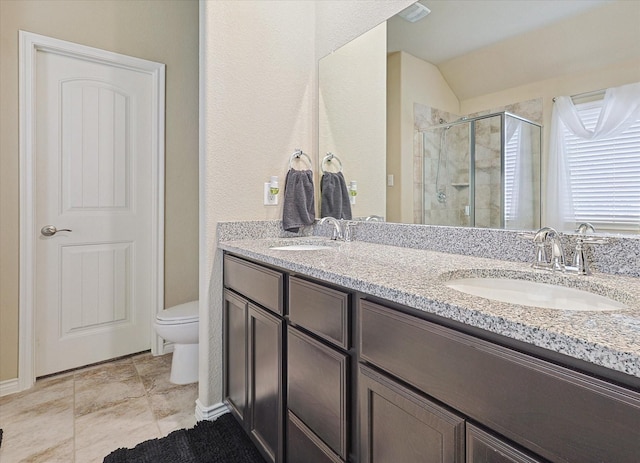 bathroom with double vanity, a stall shower, toilet, and a sink