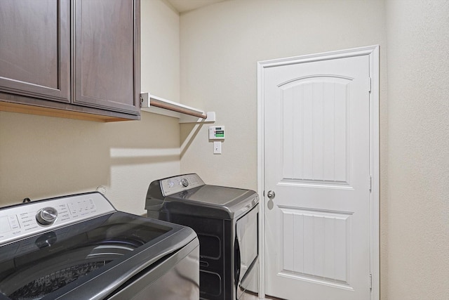 clothes washing area with washer and dryer and cabinet space