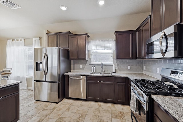 kitchen featuring light stone counters, appliances with stainless steel finishes, a sink, and visible vents