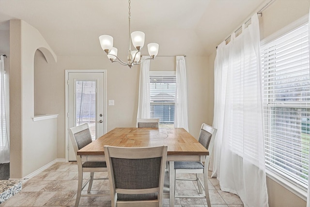 dining room with lofted ceiling, baseboards, arched walkways, and a notable chandelier