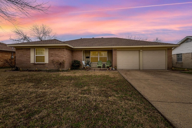 ranch-style home featuring a garage and a lawn