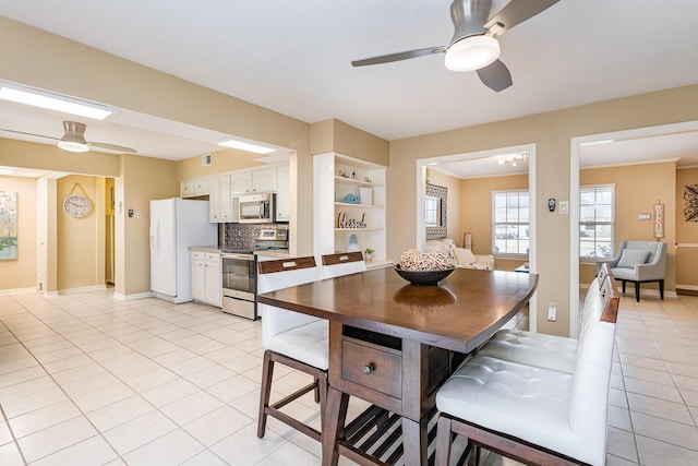 dining area with crown molding, light tile patterned floors, and ceiling fan