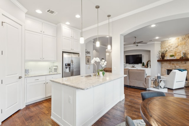 kitchen with pendant lighting, stainless steel fridge, light stone counters, and white cabinets