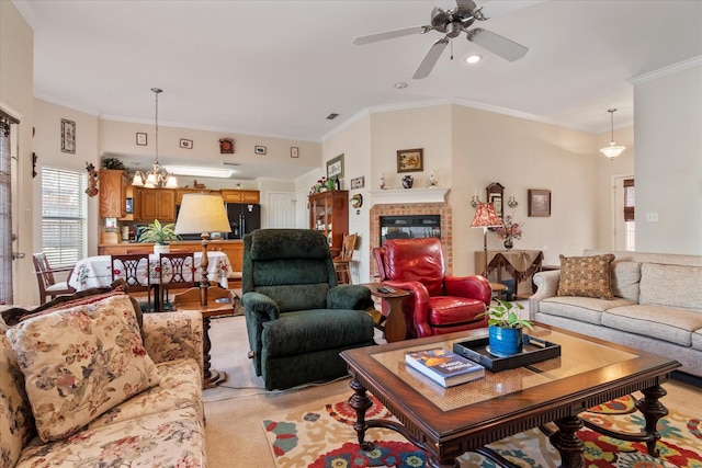 carpeted living room with a tiled fireplace, crown molding, and ceiling fan with notable chandelier