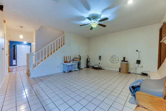 living room featuring ceiling fan, light tile patterned flooring, and a textured ceiling