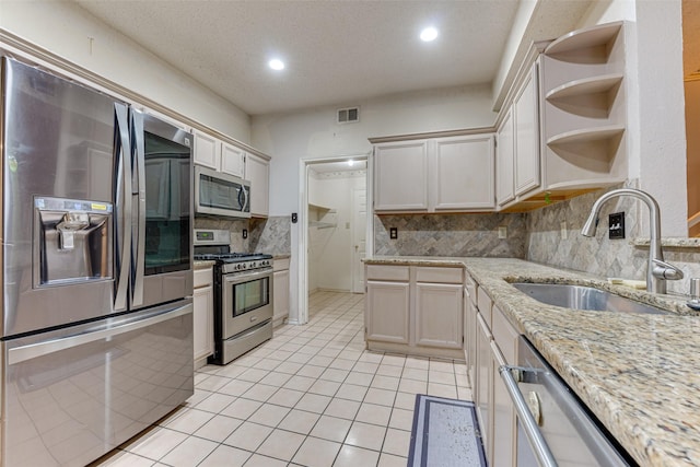 kitchen with light tile patterned floors, sink, a textured ceiling, stainless steel appliances, and tasteful backsplash