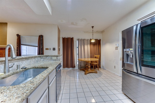 kitchen with appliances with stainless steel finishes, sink, light tile patterned flooring, pendant lighting, and light stone countertops