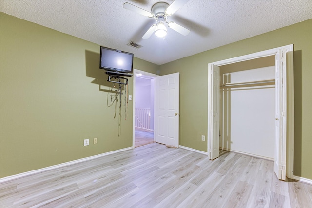 unfurnished bedroom with ceiling fan, light hardwood / wood-style floors, a textured ceiling, and a closet