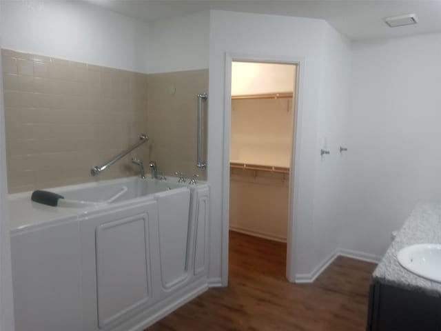 bathroom featuring a washtub, vanity, and hardwood / wood-style flooring