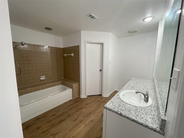 bathroom featuring hardwood / wood-style flooring, vanity, and tiled shower / bath combo