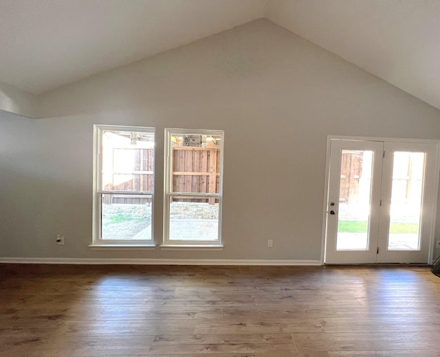 empty room with hardwood / wood-style floors, high vaulted ceiling, and a healthy amount of sunlight