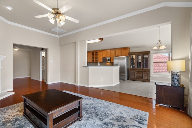 living area featuring ornamental molding, ceiling fan with notable chandelier, light wood finished floors, baseboards, and vaulted ceiling