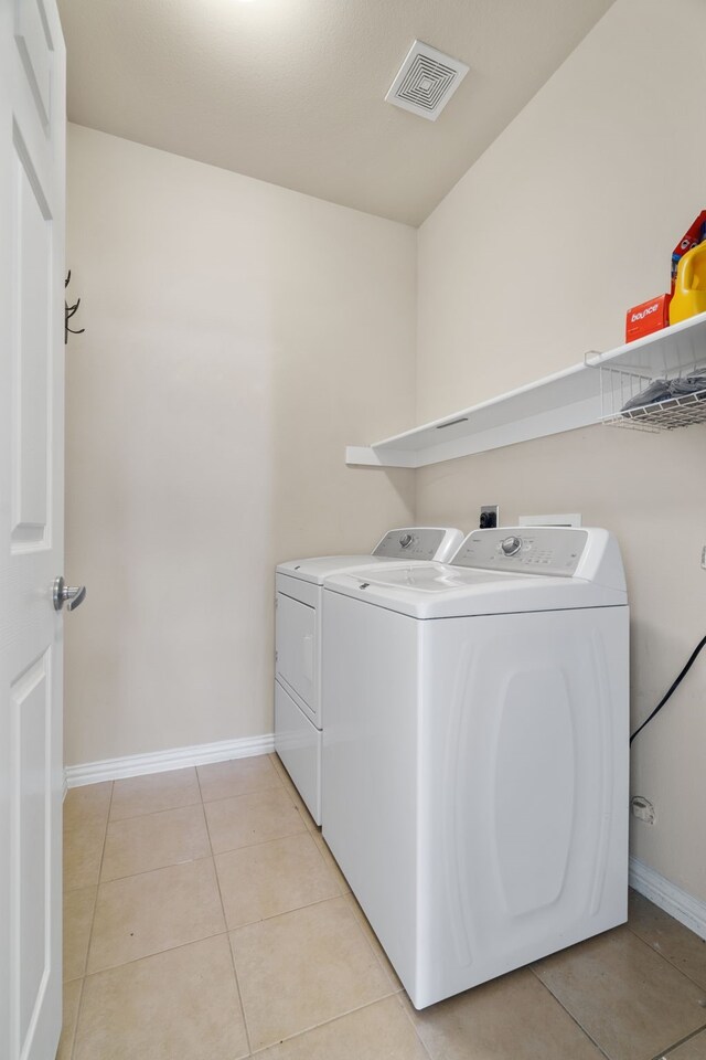 laundry area featuring light tile patterned floors, visible vents, baseboards, laundry area, and washing machine and dryer