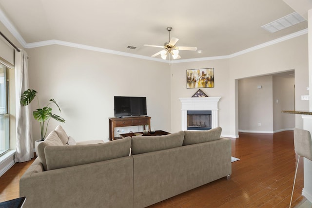 living area featuring crown molding, a ceiling fan, visible vents, and dark wood-style flooring