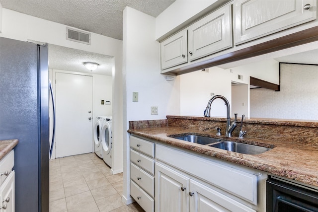 kitchen featuring sink, independent washer and dryer, a textured ceiling, white cabinets, and black fridge