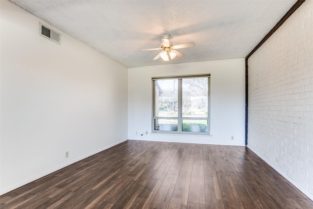 unfurnished room with ceiling fan, brick wall, dark hardwood / wood-style floors, and a textured ceiling