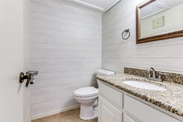 bathroom featuring vanity, wood walls, and toilet