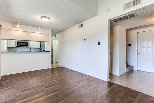 unfurnished living room with hardwood / wood-style flooring and a textured ceiling