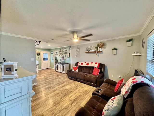 living room featuring ornamental molding, ceiling fan, a textured ceiling, and light hardwood / wood-style flooring