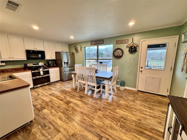 kitchen with white cabinetry, light hardwood / wood-style flooring, plenty of natural light, and appliances with stainless steel finishes