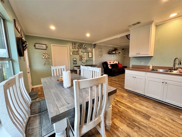 dining area featuring crown molding, sink, and light wood-type flooring