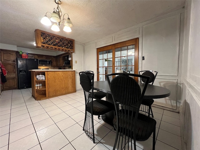 dining area with a chandelier, light tile patterned floors, and a textured ceiling