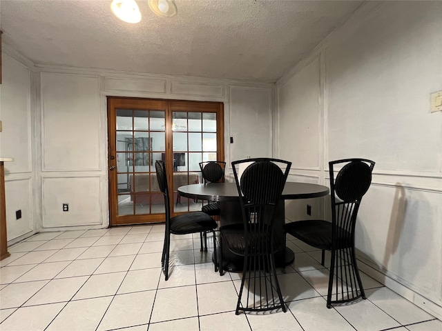 dining room featuring light tile patterned flooring, ornamental molding, and a textured ceiling