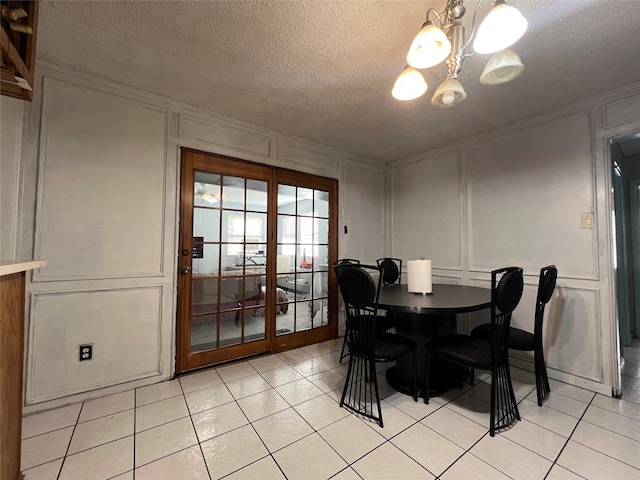 tiled dining space with a notable chandelier, ornamental molding, and a textured ceiling