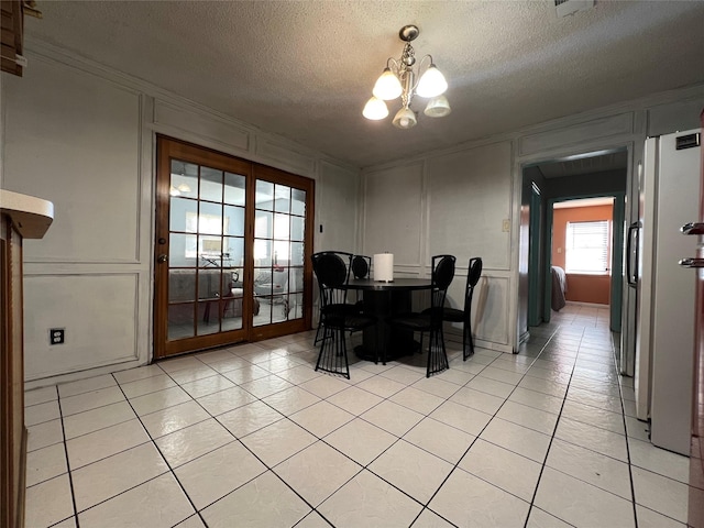 dining area with an inviting chandelier, light tile patterned floors, crown molding, and a textured ceiling