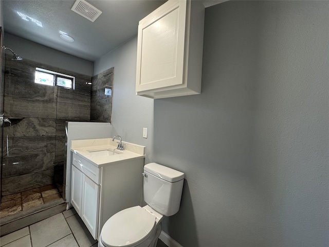 bathroom featuring vanity, toilet, and a tile shower