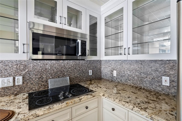 kitchen featuring black electric cooktop, light stone counters, tasteful backsplash, and white cabinets