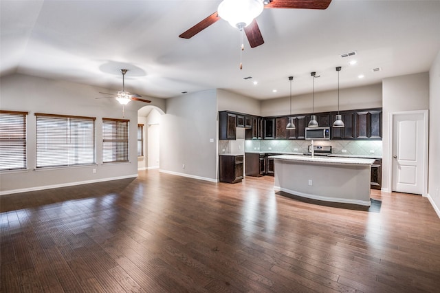 kitchen with pendant lighting, stainless steel appliances, an island with sink, and dark brown cabinets