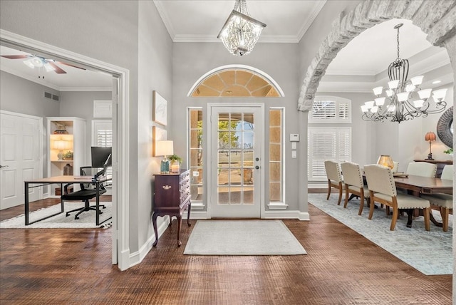 entryway with crown molding, dark wood-type flooring, and ceiling fan with notable chandelier