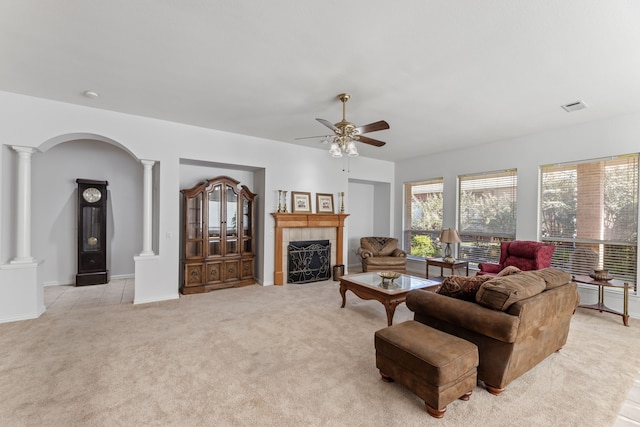 living room with ornate columns, a tile fireplace, light carpet, and ceiling fan