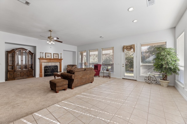 carpeted living room with ceiling fan, a fireplace, and a healthy amount of sunlight