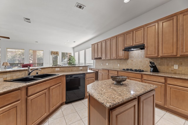 kitchen featuring light stone countertops, a center island, sink, and black appliances