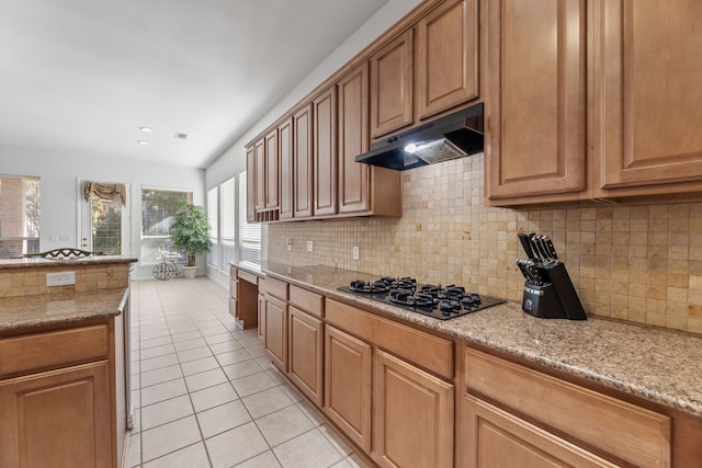 kitchen with gas stovetop, light tile patterned floors, light stone countertops, and decorative backsplash