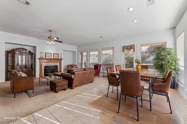 carpeted dining room featuring ceiling fan, a tile fireplace, and a wealth of natural light