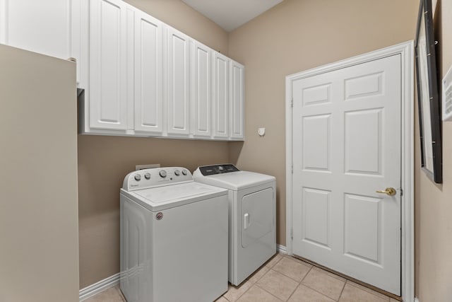 clothes washing area with cabinets, light tile patterned floors, and independent washer and dryer