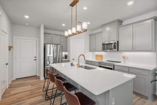 kitchen with stainless steel appliances, an island with sink, sink, and a kitchen breakfast bar