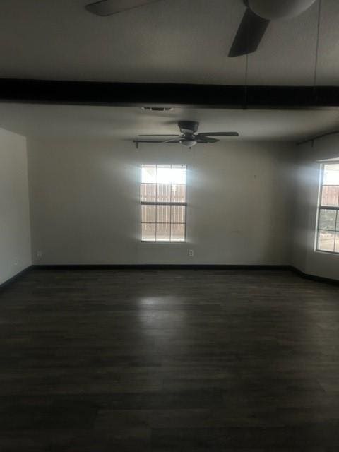 unfurnished room featuring ceiling fan, dark wood-type flooring, and beam ceiling